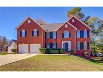 Traditional two-story brick home with a two-car garage and well-maintained lawn on a sunny day at 3071 Springfair Trott, Lithonia, GA 30038