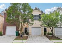 Charming two-story townhome featuring a one-car garage, well-maintained lawn, and mature landscaping at 7077 Biltmore Trce, Lithonia, GA 30058