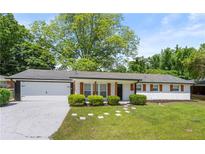 Charming single-story home with a white brick exterior, lovely landscaping, and attached garage at 2159 Fairburn Sw Rd, Atlanta, GA 30331