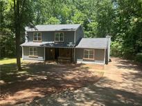 Charming two-story home with gray siding and a stone accent front porch, nestled among mature trees at 6743 Timbers East Dr, Lithonia, GA 30058