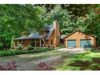 Charming log home with a two-car garage nestled in a wooded setting and featuring a welcoming front porch at 6605 Old White Mill Rd, Fairburn, GA 30213