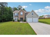 Charming two-story home featuring a brick facade, two-car garage, and a lush green lawn at 701 Fir Chase, Fairburn, GA 30213