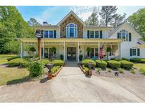 Charming two-story home with stone accents, a welcoming front porch, and lush landscaping at 12 Blackfoot Trl, Sharpsburg, GA 30277