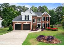 Charming brick two-story home with a two-car garage and a beautifully landscaped front yard at 523 Huntgate Rd, Woodstock, GA 30189