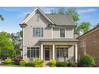 Charming two-story home featuring a covered front porch, classic gray siding, and beautifully manicured landscaping at 5981 Brundage Ln, Norcross, GA 30071