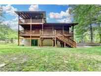 Exterior log home showcasing a multi-level deck and walkout basement on a lush green lawn at 2864 Winder Hwy, Dacula, GA 30019