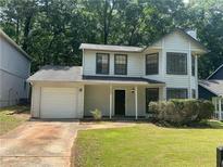 Charming two-story home with a well-maintained front lawn, attached garage, and neutral-colored exterior at 1165 Oaks Pl, Stone Mountain, GA 30083
