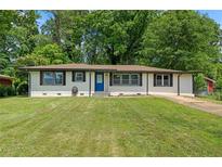 Charming single-story home with well-maintained lawn, painted white brick, contrasting trim and a blue front door at 1824 Atherton Dr, Decatur, GA 30035