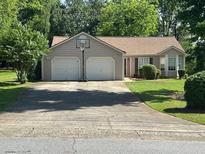 Charming single-story home featuring an attached two-car garage, manicured lawn, and traditional architectural details at 3217 New Rutledge Nw Rd, Kennesaw, GA 30152
