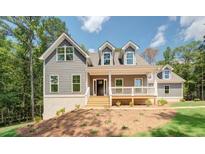 Charming two-story home with a welcoming front porch and well-manicured lawn in a wooded setting at 220 Nicklaus Cir, Social Circle, GA 30025