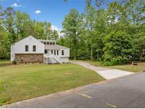 Charming white home with stone accents, manicured lawn, and driveway, nestled amongst lush trees at 2920 Alberta Dr, Marietta, GA 30062