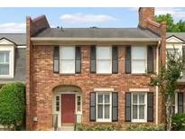 Charming brick townhome featuring multi-pane windows with black shutters and a red front door at 27 Jefferson Hill Ne Pl, Atlanta, GA 30342