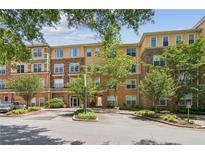 Exterior view of a multi-story condo with stone and stucco facade, landscaped grounds, and covered entryway at 10 Perimeter Summit Ne Blvd # 4243, Brookhaven, GA 30319