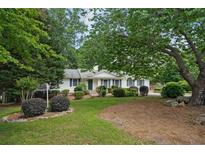 Charming single-story home with a well-manicured lawn, lush greenery, and mature trees providing shade at 2384 Shadowood Sw Dr, Conyers, GA 30094