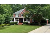 Charming two-story brick home featuring a manicured lawn, welcoming porch, and lush landscaping at 3256 Waterhouse Nw St, Kennesaw, GA 30152