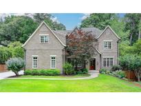 Beautiful brick home featuring a manicured lawn, mature trees, and professional landscaping at 272 Lake Forrest Ne Ln, Atlanta, GA 30342