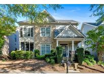 Charming two-story home featuring a stone facade, covered porch, and well-maintained landscaping at 4845 Backbay St, Suwanee, GA 30024