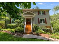 Traditional two-story home with red door, brick stairs, white railing, and lush landscaping at 9041 Par Dr, Douglasville, GA 30134