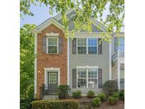 Charming two-story townhome featuring a mix of brick and siding, complemented by gray shutters and well-manicured landscaping at 9155 Nesbit Ferry Rd # 65, Alpharetta, GA 30022