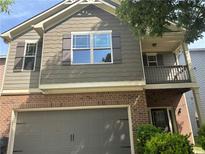 Two-story home featuring a brick and siding exterior with a front porch and attached garage at 678 Sweet Ashley Way, Loganville, GA 30052