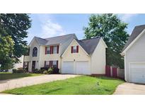 Charming two-story home with a two-car garage, red shutters, and a well-manicured lawn at 130 Hazelhurst Dr, Covington, GA 30016