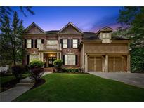 Stunning two-story brick home with a well-manicured lawn and a three-car garage, creating an inviting curb appeal at 4840 Spring Park Cir, Suwanee, GA 30024
