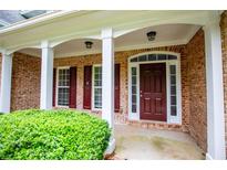 Inviting front entrance with a brick facade, white columns, and a classic dark wood door at 5995 Azalea Ridge Dr, Douglasville, GA 30135