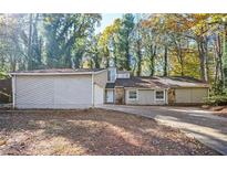 Inviting single-story home featuring stone accents and a large, private front yard surrounded by mature trees at 5474 Post Road Pass, Stone Mountain, GA 30088