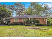 Charming single-story brick home featuring a well-manicured lawn and mature trees in a serene setting at 894 Nottingham Dr, Avondale Estates, GA 30002
