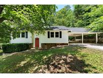 Charming single-story home with a red front door, carport, and lush greenery at 128 Reynolds Bridge Rd, Kingston, GA 30145