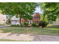 Beautiful brick home with mature trees, manicured lawn, and a two-car garage on a sunny day at 1300 Sever Woods Dr, Lawrenceville, GA 30043