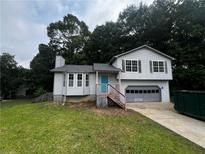 Split level home showcasing light siding, a front-facing garage, and a lawn at 1504 Colt Ridge Se Ln, Mableton, GA 30126