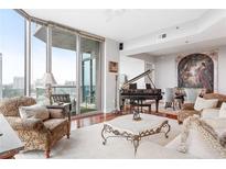 Bright living room featuring floor to ceiling windows, hardwood floors, and a grand piano at 2795 Peachtree Ne Rd # 2101, Atlanta, GA 30305