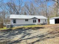 Charming single-story home with white siding, metal roof and a quaint porch, nestled in a wooded setting at 7301 Staton Se Pl, Acworth, GA 30102