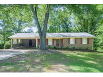 Charming brick home featuring a covered carport and a well-manicured lawn with mature trees at 2668 Kings Way, Lawrenceville, GA 30044