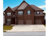 Charming two-story brick home featuring a three-car garage and well-manicured lawn against a bright blue sky at 419 Woodmill Way, Atlanta, GA 30331
