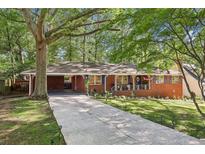 Charming brick home featuring a long driveway and lush landscaping with a cozy front porch at 5222 Skyline Dr, Stone Mountain, GA 30083