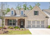 Charming brick home featuring a welcoming porch, manicured lawn, and a two-car garage at 1409 Bluffs Ridge Way, Canton, GA 30114