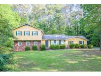 Charming two-story home with a brick facade and a well-manicured lawn surrounded by lush greenery at 2037 Cliffton Ter, Snellville, GA 30039
