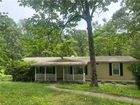 Charming single-story home featuring a covered front porch and surrounded by lush greenery and mature trees at 710 Seals Rd, Dallas, GA 30157