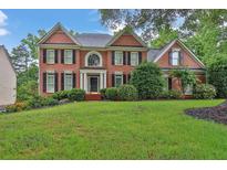 Traditional two-story brick home with a lush green lawn and manicured landscaping at 283 Heron Lake Ct, Lawrenceville, GA 30043