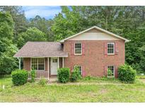 Charming two-story brick home featuring a covered front porch and red shutters surrounded by lush greenery at 1576 King Mill Rd, Mcdonough, GA 30252
