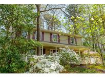 Charming two-story home with mature trees, lush landscaping and front porch at 6795 Brandon Mill Rd, Atlanta, GA 30328