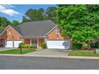 Charming brick home featuring an attached two-car garage, well-manicured lawn, and mature trees at 8675 Hope Vine, Roswell, GA 30076