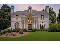 Stately white home featuring a manicured lawn, beautiful landscaping, a symmetrical facade, and black-framed windows at 4011 Charrwood Trce, Marietta, GA 30062
