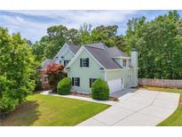 Well-maintained two-story home featuring green siding, black shutters, manicured lawn and a wide concrete driveway at 1213 Fairwinds Dr, Loganville, GA 30052