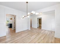 Bright dining room with white wainscoting, hardwood floors and unique lighting fixture at 4377 Hosch Reserve Dr, Buford, GA 30519
