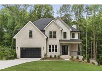 Charming two-story home featuring a brick facade, black accents, and a manicured front lawn at 3915 Ashley Trace Sw Ct, Lilburn, GA 30047