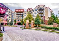 A multi-story condo building featuring balconies, mature trees and manicured landscaping at the entrance at 200 River Vista Dr # 120, Atlanta, GA 30339