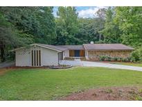 Charming single-story home with stone and brick exterior, surrounded by lush greenery and a well-manicured lawn at 4717 Westhampton Dr, Tucker, GA 30084